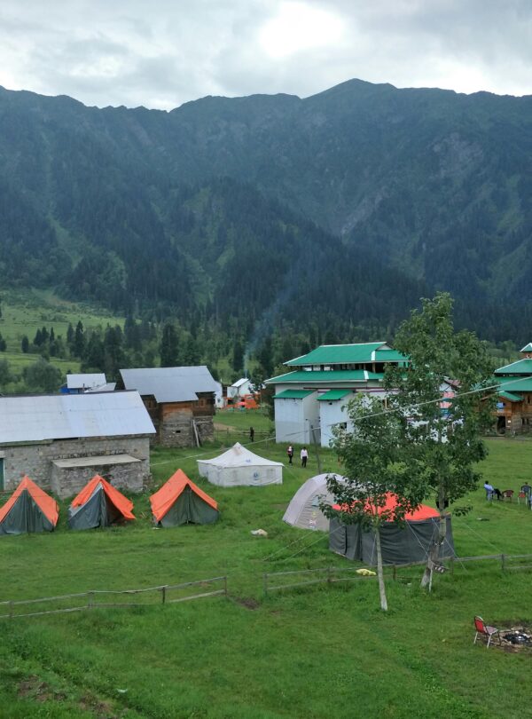 Explore the picturesque tents and cabins in Arang Kel against a stunning mountainous backdrop.