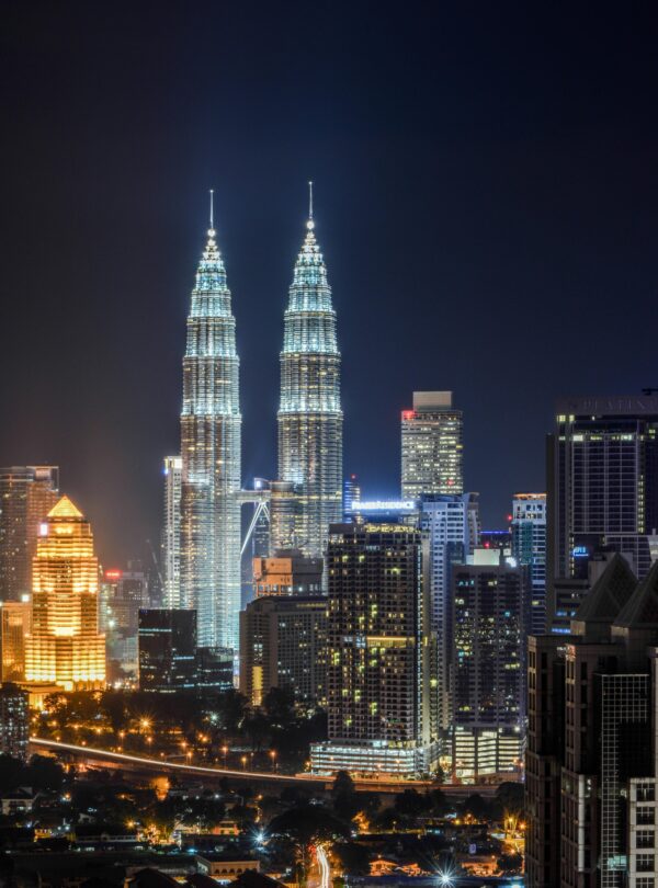 Stunning cityscape of Kuala Lumpur featuring the iconic Petronas Twin Towers illuminated at night.