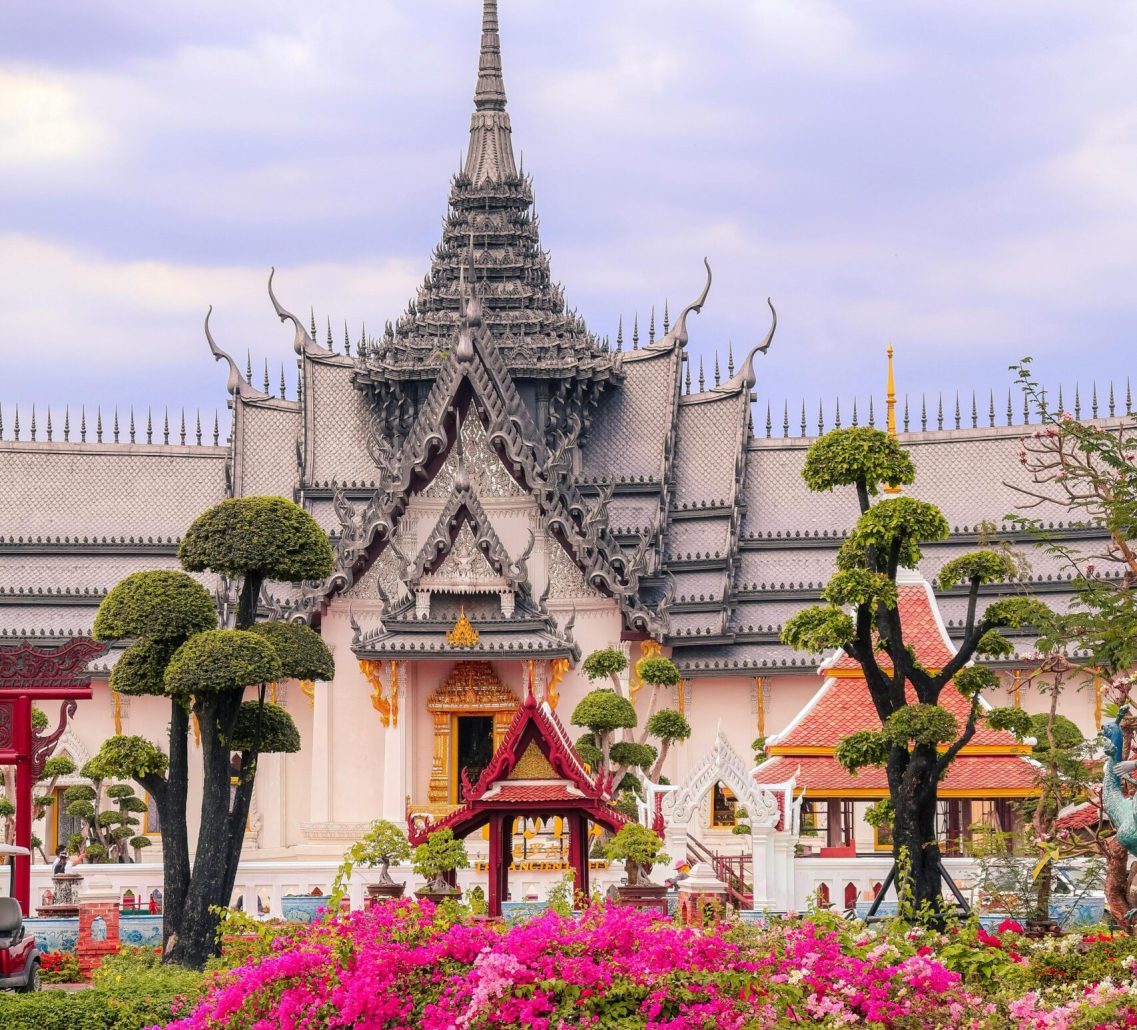 Beautiful Thai temple surrounded by garden blooms in Samut Prakan, Thailand, captured during the day.